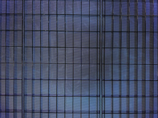 Close up of building glass window pattern with black metal frames in blue color. Blue tinted glass color as curtain wall. Seamless background texture.