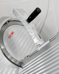 Sleek chrome meat slicer glints in sterile kitchen light, evoking culinary precision, Oktoberfest...