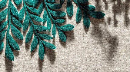 Teal felt leaves arranged on beige textile, casting shadows