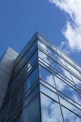 Corner of a modern glass building against a clear blue sky.