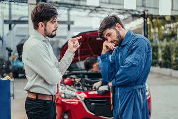 Customer arguing with stressed car mechanic in auto repair shop over poor service and warranty...