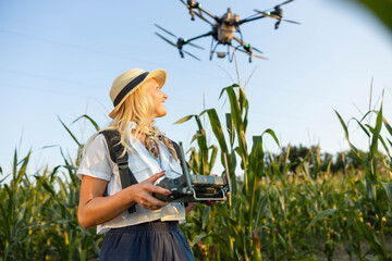 A woman joyfully pilots a drone over a cornfield, showcasing modern agricultural technology in vibrant green surroundings. © Dejan