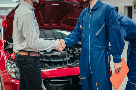 Car owner shaking hands with professional mechanic in clean workshop, symbolizing successful repair, trust, and complete customer satisfaction in automotive service industry.