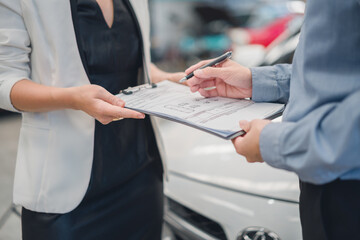 Young man completing car purchase signing with dealer agent, capturing trust, service quality, and professionalism in automotive, insurance, and finance transaction process.