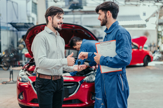 Smiling car owner receiving keys from mechanic after repair, symbolizing quality service, trust, and customer satisfaction in automotive maintenance.
