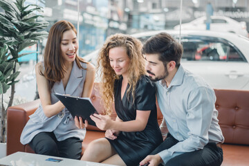 Young couple reviewing purchase details on clipboard with sales agent, showing customer satisfaction, trust, and professional consultation in automotive sales.
