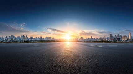 Empty asphalt road leading to a city skyline at sunset