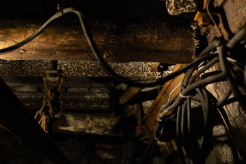 Old timber supports, rusted chains and electrical cables inside an abandoned underground mine tunnel