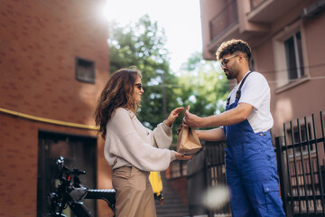Delivery man delivering package to woman using electric bicycle in the city