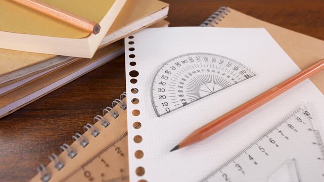 Closeup of protractor, triangle ruler measuring tools, pencil isolated on white graph chart paper and books.