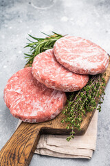 Frozen raw Hamburger beef Patty, uncooked mincemeat. grey background. top view