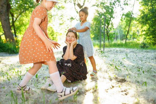 Woman and children playing with poplar fluff outdoors in summer