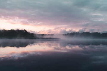 Fototapeta premium Misty sunrise over a tranquil lake.