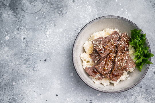 Delectable yakiniku feast, featuring a variety of marbled beef cuts and rice. A culinary journey that captures the essence of Japanese grilling traditions. grey background. top view