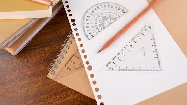 Closeup of protractor, triangle ruler measuring tools, pencil isolated on white graph chart paper and books.