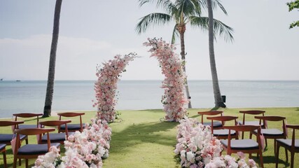 Romantic beach wedding setup with elegant wooden chairs, pastel floral arch, and ocean view under palm trees, perfect for destination weddings, elopements, and intimate seaside ceremonies.