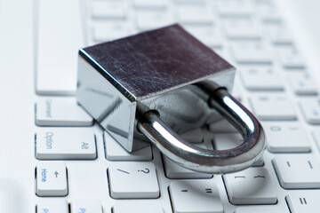 Silver padlock on a white keyboard. Digital security, data protection, and online safety concept.