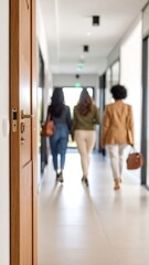 Three women walk away down a hallway, view from doorway