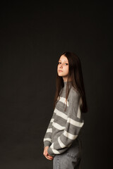Woman in gray sweater in studio on black background