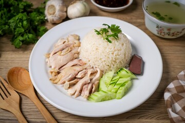 Chicken and rice with coriander and cucumber with sauce and soup in a white plate, hainanese chicken rice, thai called khao man gai, asian food, thai food