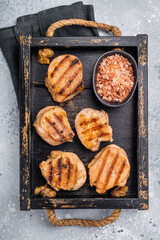 Tender char grilled pork medallion steak, perfect for adding a touch of elegance to your dinner plate.grey background. top view