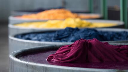 Colorful fabric dyeing process with vibrant cloth in large metal vats, industrial textile production, creative atmosphere