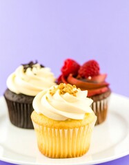 Three assorted cupcakes on a white plate against a purple background