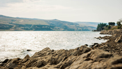 Rocky shore of the Tbilisi Sea on a summer morning. Sparkling water, distant hills and warm light create a calm, peaceful mood perfect for travel and nature themes