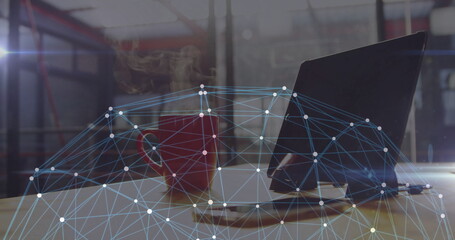 Displaying red coffee mug steaming beside laptop on desk in office with digital network overlay © vectorfusionart