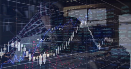 Leaning analyst examining market data on monitor and laptop at office desk, with translucent charts