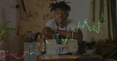 Sitting tailor wearing denim apron resting arms on machine at studio, with neon stock chart overlay