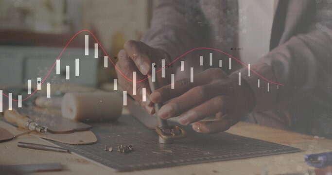 Punching craftsman using metal hole punch on workbench with brown leather strap, analytics overlay - Powered by Adobe