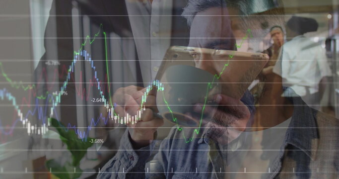 Denim-shirted Asian man sipping coffee from mug in office, with tablet chart overlay