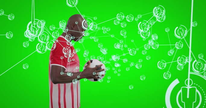 Holding soccer ball, male athlete wearing red-striped jersey focusing on network overlay in studio