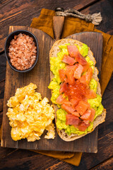 Sandwich with smoked salmon, trout, avocado and red caviar. wooden background. top view