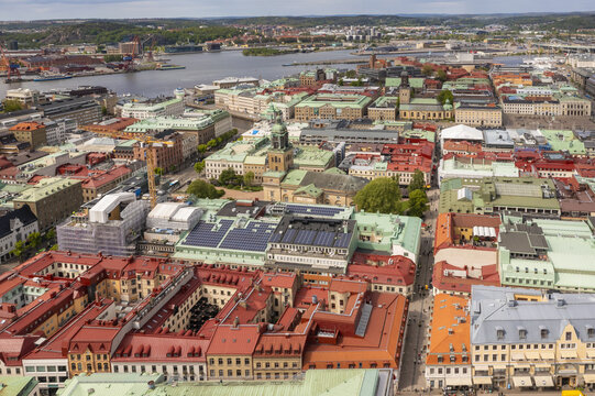 Aerial view of red-tiled roofs and verdant treetops meet the serene waters of the Gota Alv river, creating a vibrant tapestry of urban life, Gothenburg, Vastra Gotaland, Sweden.