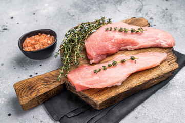 Ready for cooking pork loin fillets, raw tenderloin meat on a wooden board. Gray background. top view