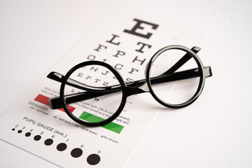 Glasses on eye testing exam chart to check eyesight accuracy of reading.