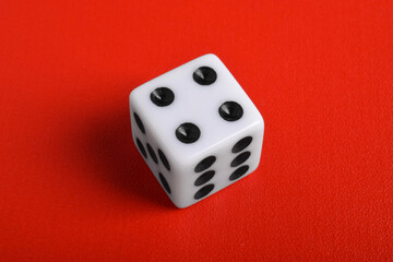 One white dice isolated on red background