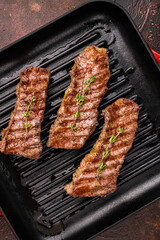 Grilled Tri tip steaks, marbled beef meat on pan with herbs. brown background. top view
