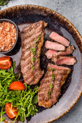 BBQ Grilled skirt or machete Steak, beef meat on a plate with salad. grey background. top view