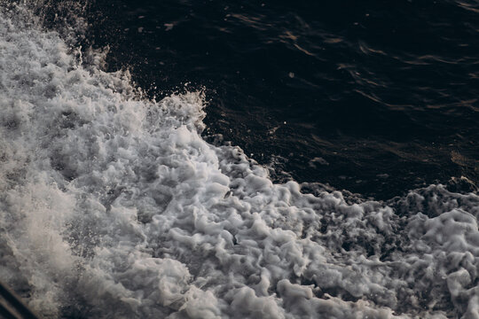 A close-up, abstract view of churning sea foam and waves, showing the dynamic texture and movement of the ocean water.