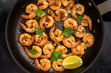 Fried Shrimps Prawns with garlic and butter in a skillet. Black background. Top view