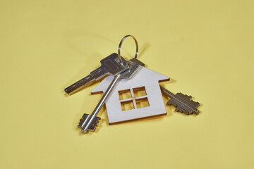 Keys with house shaped keychain on yellow background. Concept of construction and leasing of residential premises, occupancy, sale and leasing