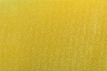 Detail of texture of synthetic yellow sponge with tiny holes