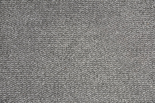 Textured background of gray carpet speckled with short-pile strands