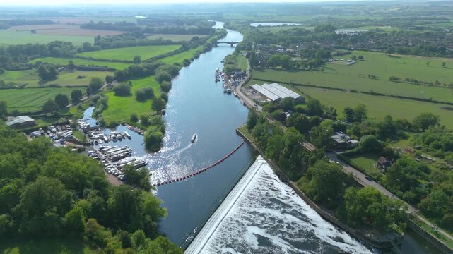 Aerial drone footage of canal narrowboat on River Trent at Gunthorpe weir rural landscape green fields sunny evening Nottingham england UK
