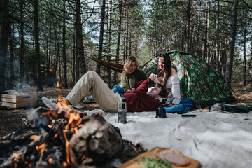 Fototapeta premium Friends enjoying a campfire and nature with a tent in a forest setting
