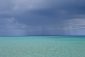 Fototapeta premium Cobalt Blue Sea and Sky with Localized Rain Cloud, Miyakojima, Okinawa, Japan