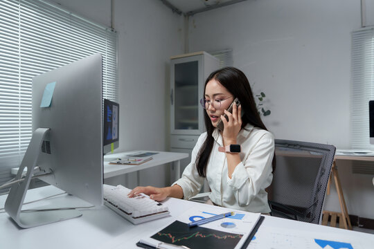 Businesswoman working on computer and talking on phone in office